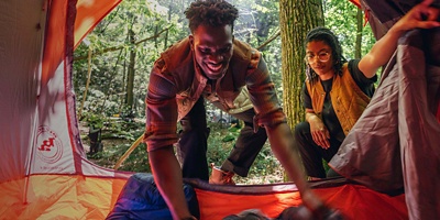 Two explorers setting up sleeping bags in a tent