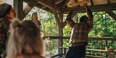 man hanging from fingertips in a park pavillion