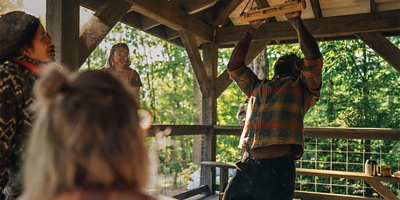 man hanging from fingertips in a park pavillion