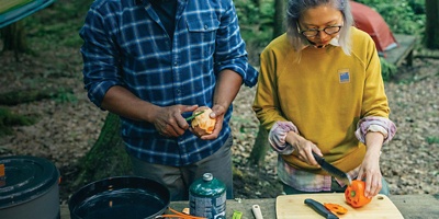 Two campers meal prepping in the woods