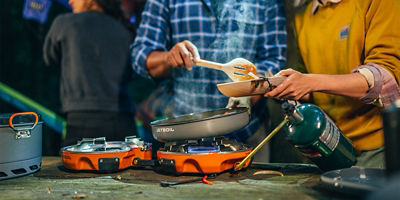 Two people plating food from camp stove and pans