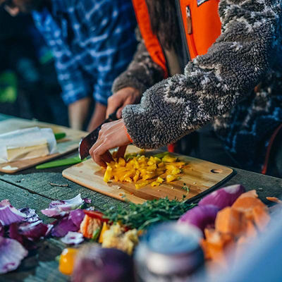 Camper meal-prepping food in the woods on a picnic table