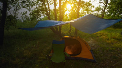 a tent under a tarp in forest at sunset