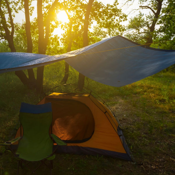 a tent under a tarp in forest at sunset