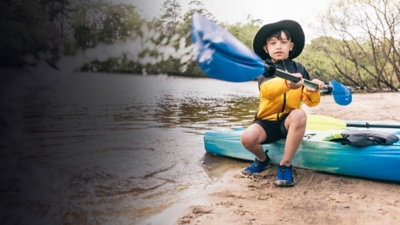 A kid plays with a kayak paddle