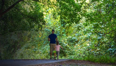 A man with a blue shirt walking with his daughter in a pink shirt on the hiking trail at the Chattahoochee River National Recreation Area in Sandy Springs 