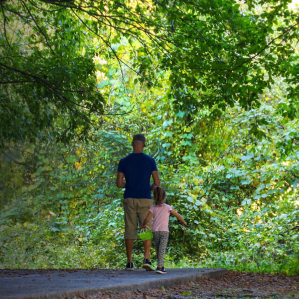 A man with a blue shirt walking with his daughter in a pink shirt on the hiking trail at the Chattahoochee River National Recreation Area in Sandy Springs 