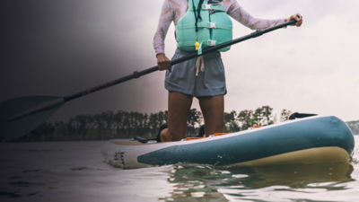 Detail of a SUP paddle boarder on a lake