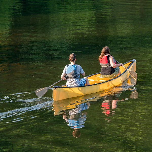 Two people paddling in yellow canoe 