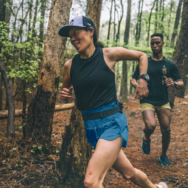 Two runners run in the forest