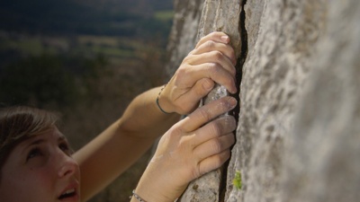 A woman crack climbing detail of a hold