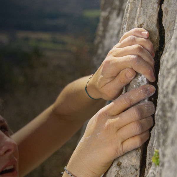 A woman crack climbing detail of a hold