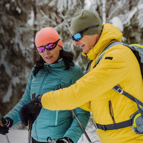 Senior couple checking smartwatch during winter skiing.