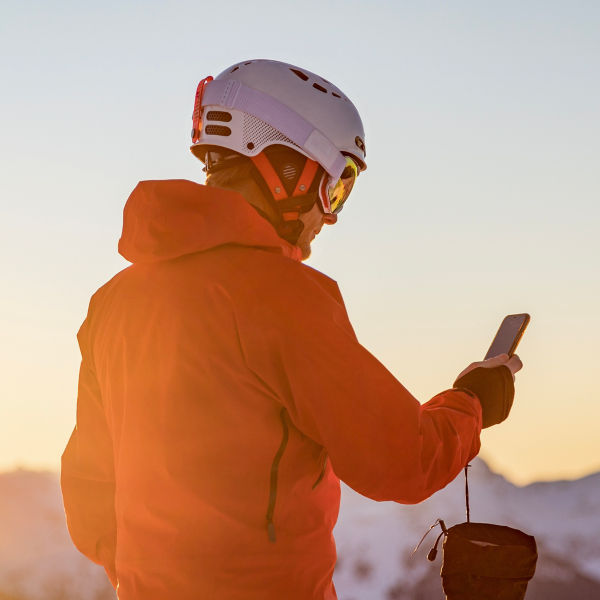 Male skier in the mountains looking at his phone