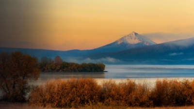 Autumn landscape of upper Klamath Lake draped in early dawn light with rising fog and Mt. McLaughlin in the backgrouns covered with a light dusting of snow.