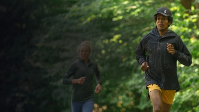 Two runners running on a trail in the forest