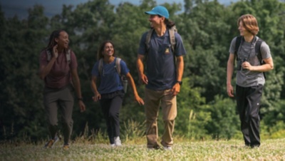 A group of friends hike together outside in the summer