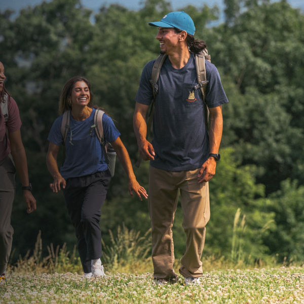 A group of friends hike together outside in the summer