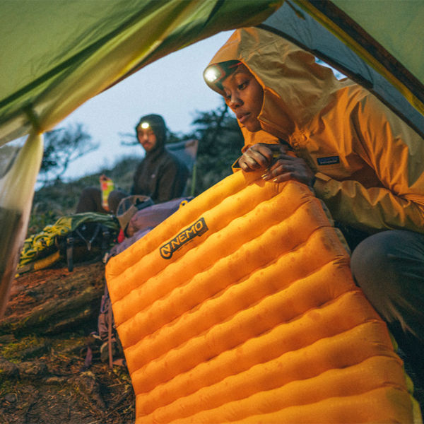 A woman blows up her sleeping pad in a tent