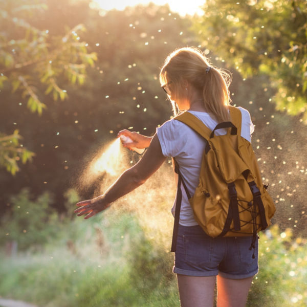 Woman is applying insect repellent against mosquito and tick on her hand during hike in nature. 