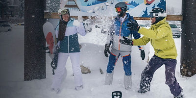 Three friends smile and have fun with their skis and snowboards at a resort