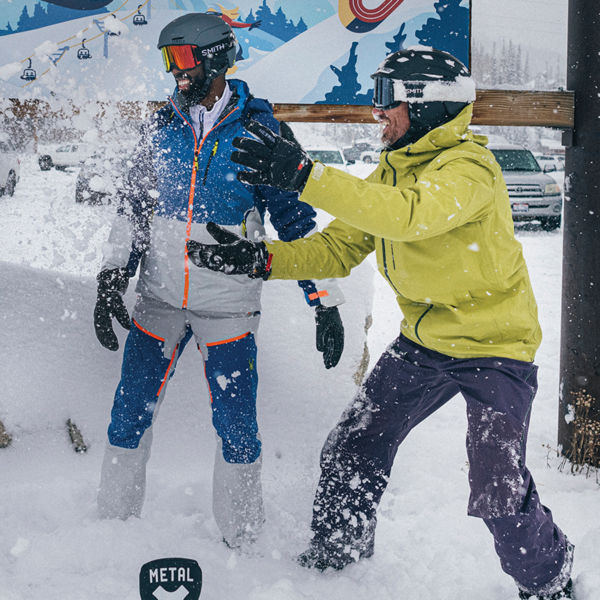 Three friends smile and have fun with their skis and snowboards at a resort