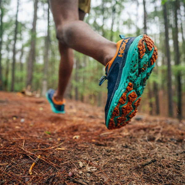 A shoe detail of a trail runner along a wooded path
