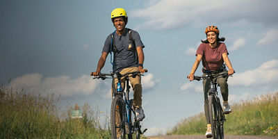 Two bikers biking on a gravel road