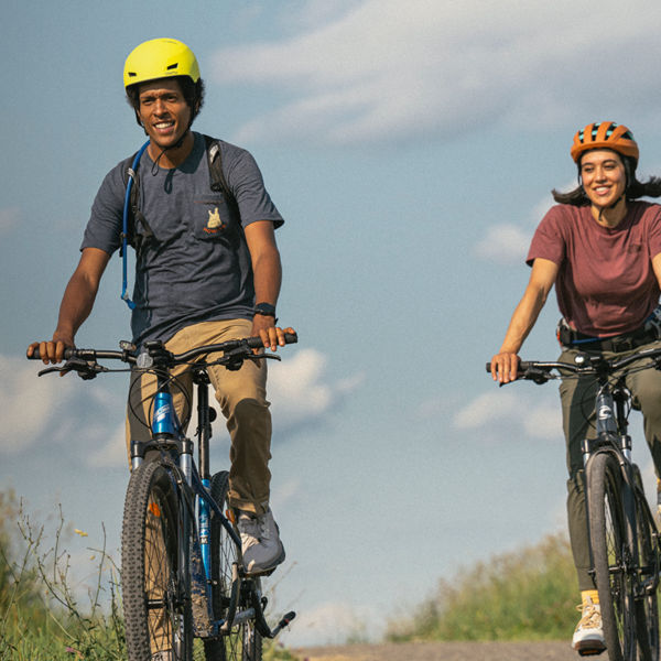 Two bikers biking on a gravel road