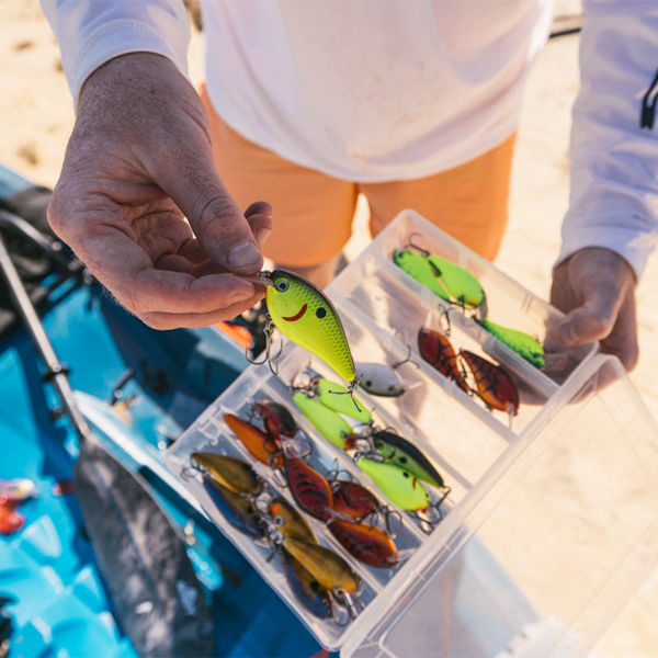 A man picks out fishing bait from a tackle box