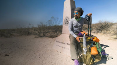  Derick Lugo sits next to a CDT trail sign