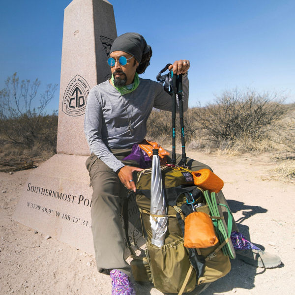  Derick Lugo sits next to a CDT trail sign