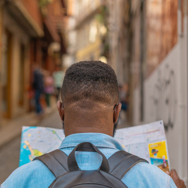 Tourist man looking at map to find directions walking in old streets of Portugal city. 