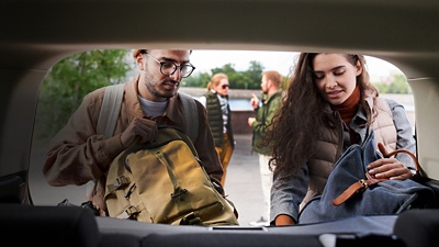 Young  friends loading bags into car trunk while preparing for travel