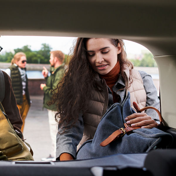 Young  friends loading bags into car trunk while preparing for travel
