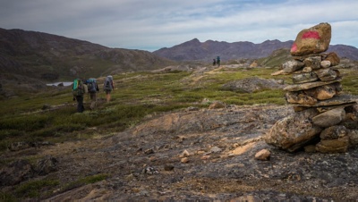 Hikers on  the Arctic Circle Trail in Greenland with a trail cairn