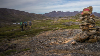 Hikers on  the Arctic Circle Trail in Greenland with a trail cairn