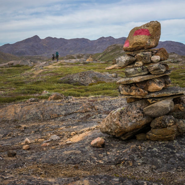 Hikers on  the Arctic Circle Trail in Greenland with a trail cairn
