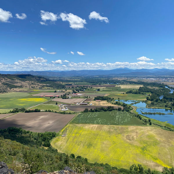 Aerial View of the lush green Rogue Valley in Southern Oregon from atop Table Rock Plateau with fields of green and yellow wildflowers.