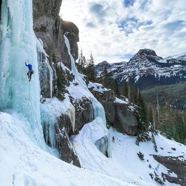 Molly Kawahata ice climbing with the mountains behind her