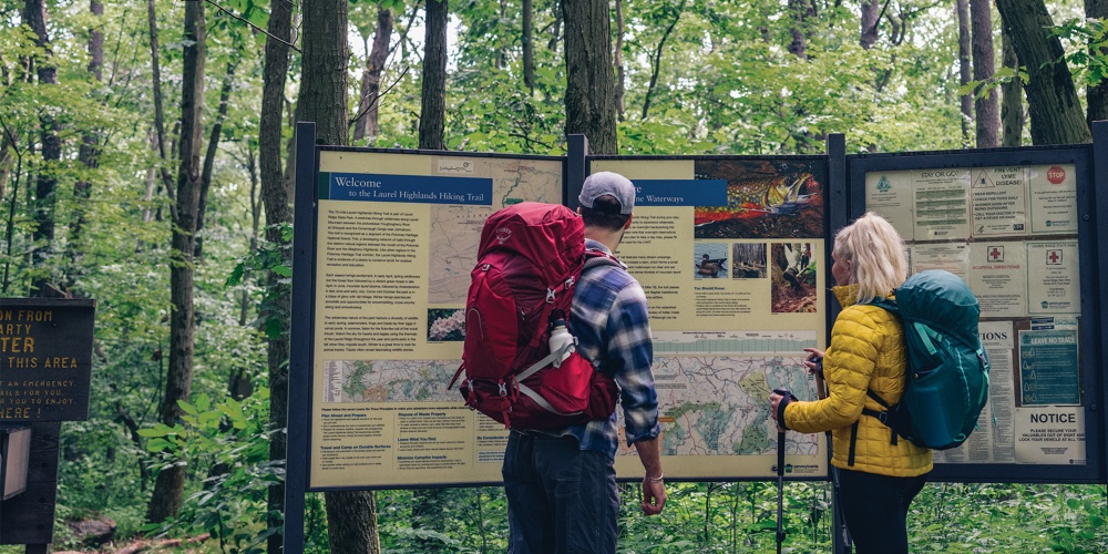 Young male caucasian traveler in red hat and summer hiking outfit enjoying  a waterfall during his single trip at the wooden mountains, back view.  Photos