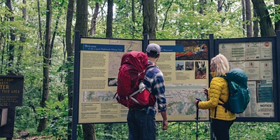Two hikers consulting a map in a park with backpacks and treking poles