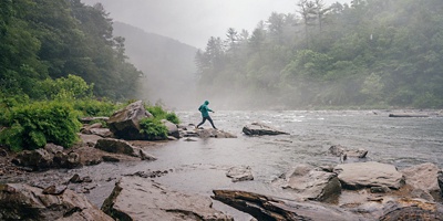 Hiker by the river in the rain