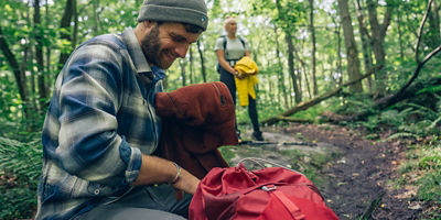 Guy going through his daypack in the woods