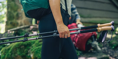 A woman holding trekking poles in the forest