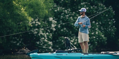 a man fly fishing while standing on a boat