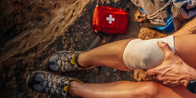 A woman holds her leg with an elastic bandage during a hike