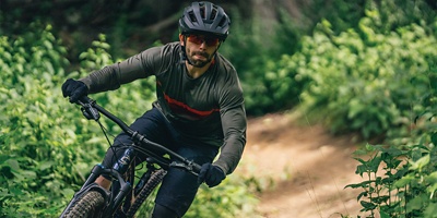 A man biking down a dirt path in the woods