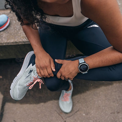 A woman wearing a smartwatch, crossing her leg over her knee.