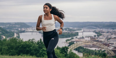 A woman running with a cityscape and river behind her